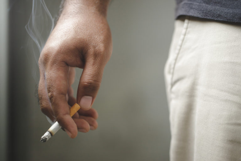 Mão de homem segurando um cigarro