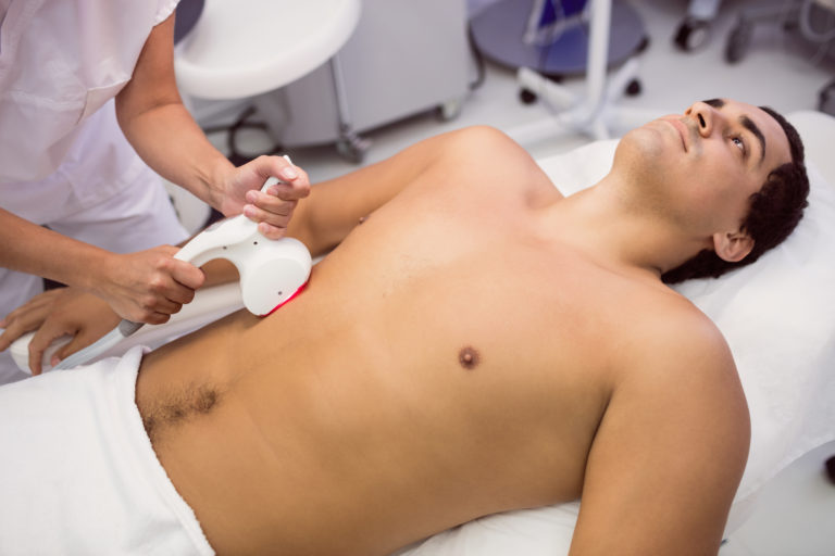 Homem deitado na maca fazendo terapia de ondas de choque