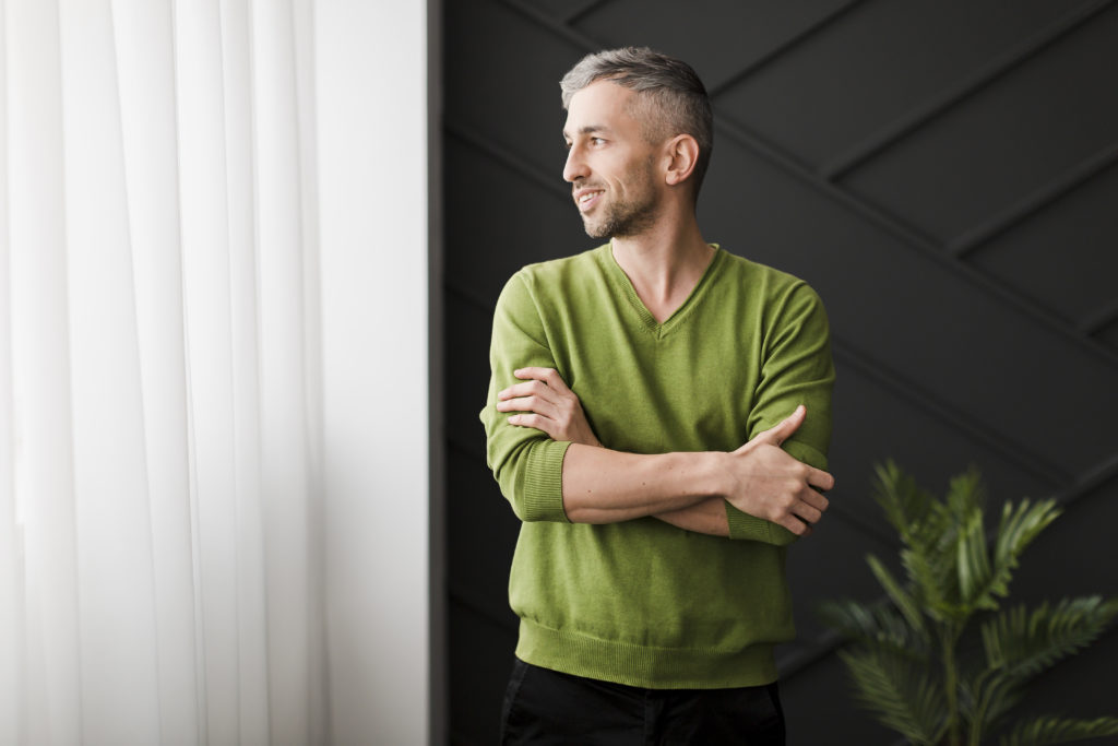 Homem com camiseta verde olhando para janela