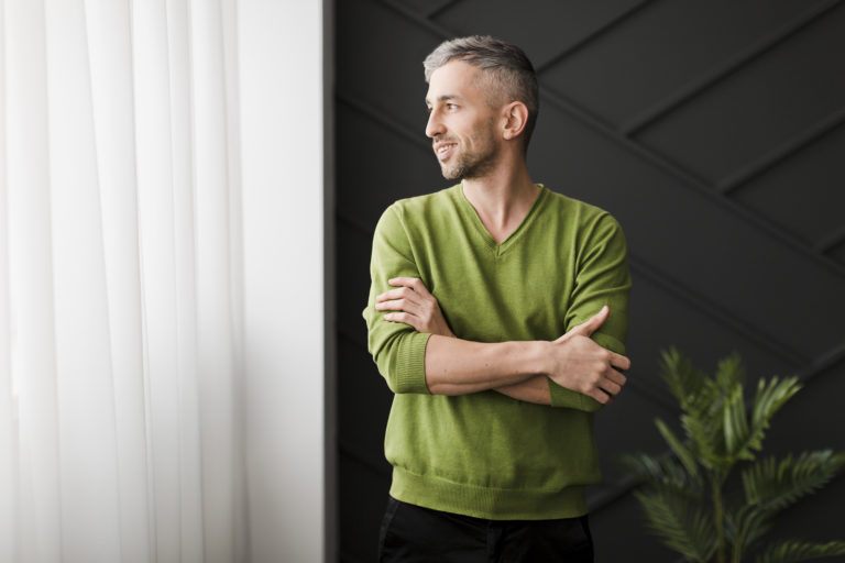 Homem com camiseta verde olhando para janela